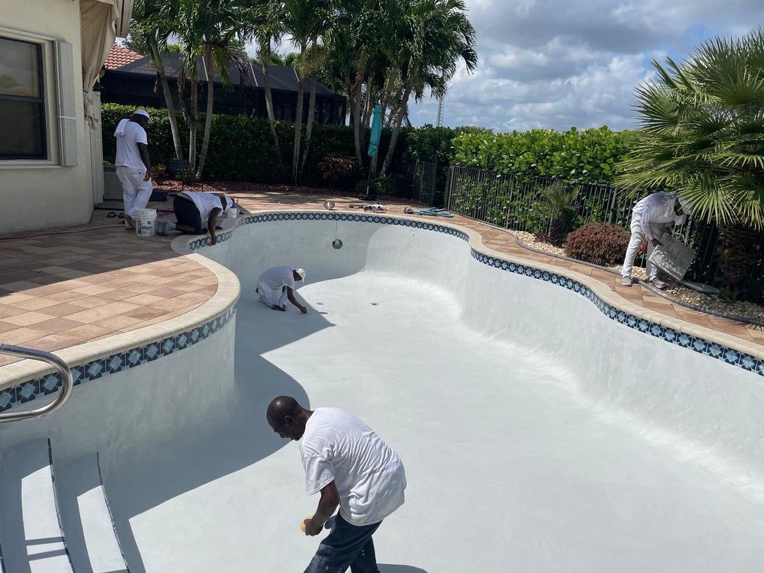 Crew applying fresh white plaster finish to a pool