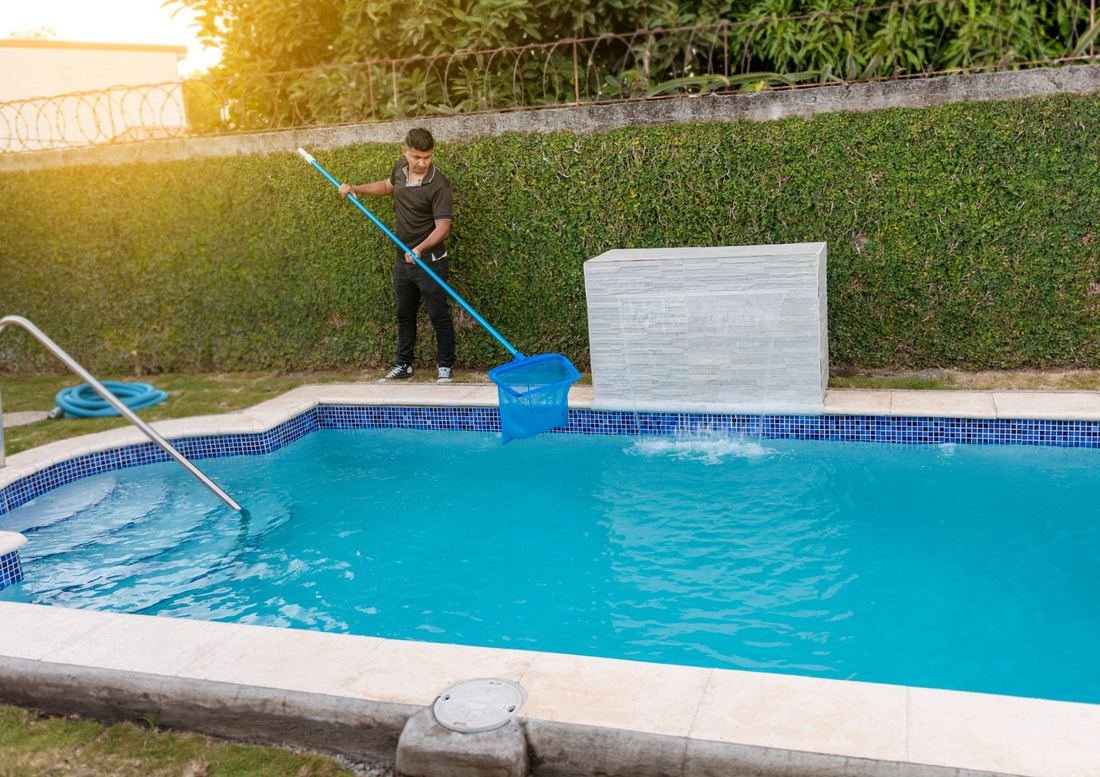 Technician skimming and cleaning a residential pool